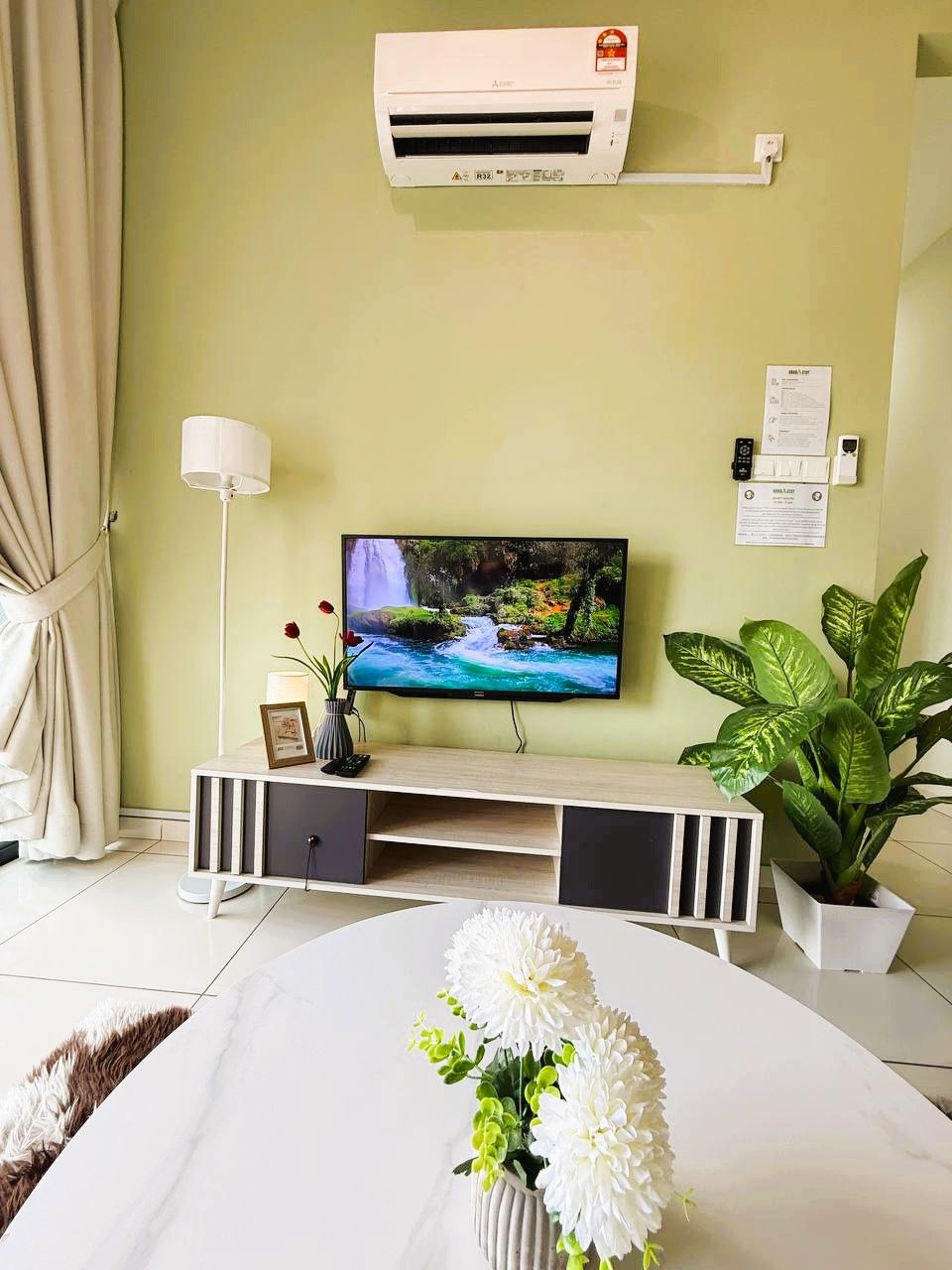 Un salon équipé d’un téléviseur, d’un climatiseur et d’une plante en pot.