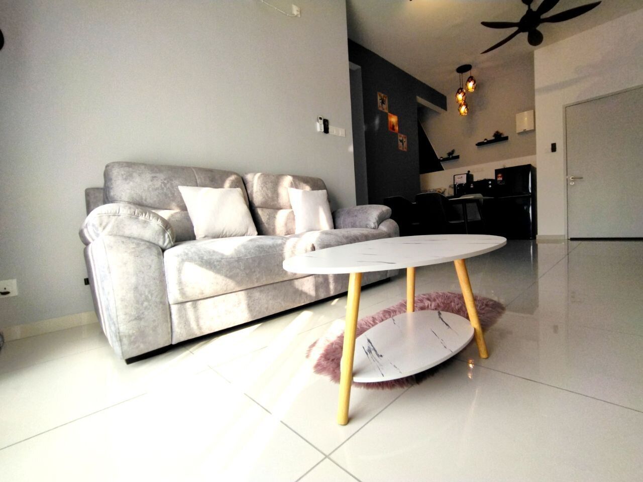 A modern living room with a grey sofa, a white coffee table, and a ceiling fan.