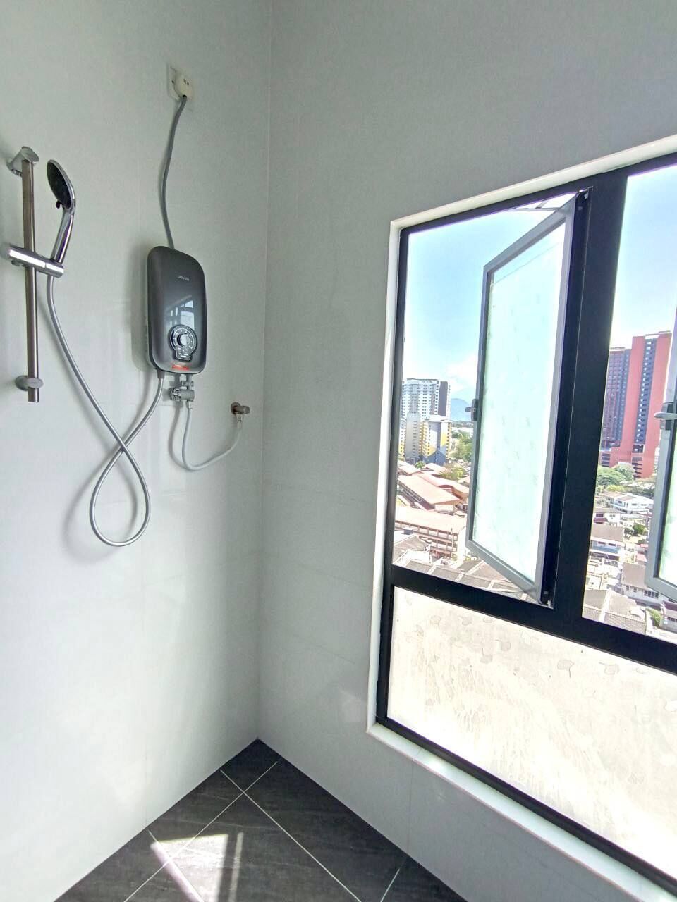 A bathroom with a window, a shower, and a visible cityscape outside.