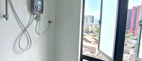 A bathroom with a window, a shower, and a visible cityscape outside.