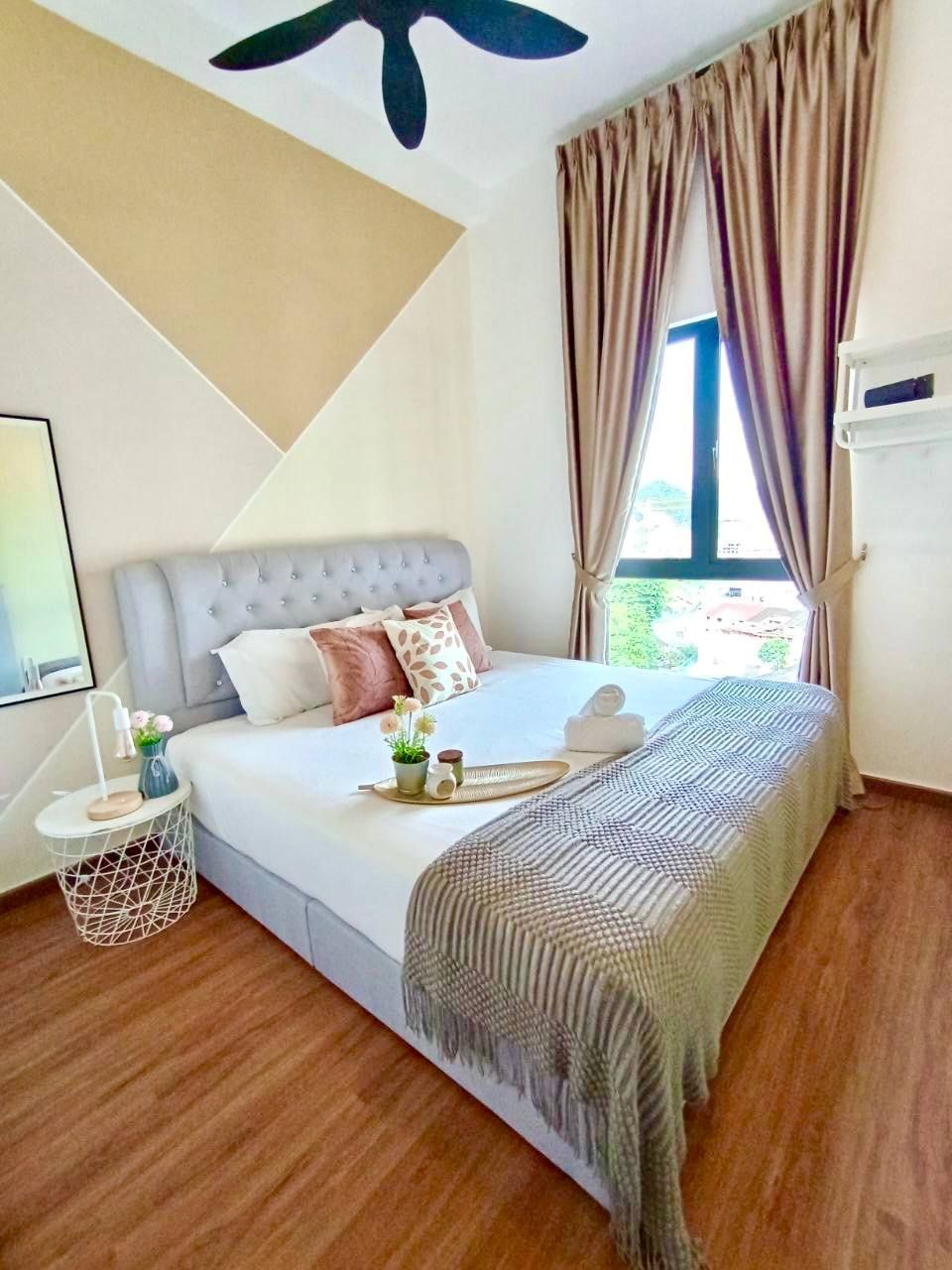 A bedroom with a bed, a bedside table, a window with curtains, and a ceiling fan.