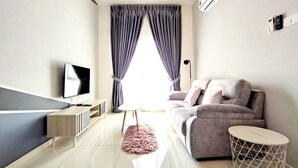 A modern living room with a flat-screen TV, grey sofa, and a round side table. - Infinity View Suites l The Horizon Ipoh l by Grab A Stay - 1-8 Pax (Ipoh)