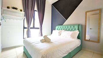 A neatly made bed with white linens and pillows, a teal headboard, and a window with curtains.