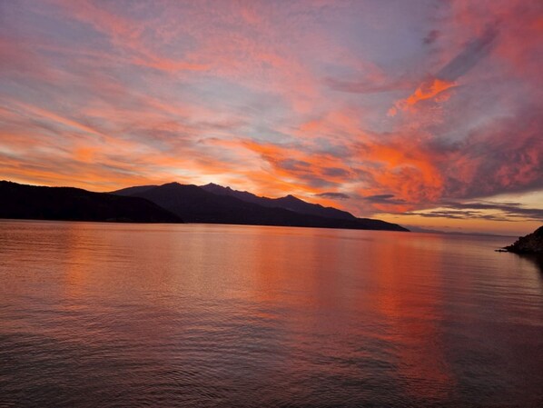 A calm lake with mountains in the background and a colorful sky.