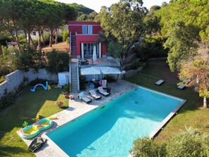 A two-story house with a swimming pool, outdoor seating, and a slide.