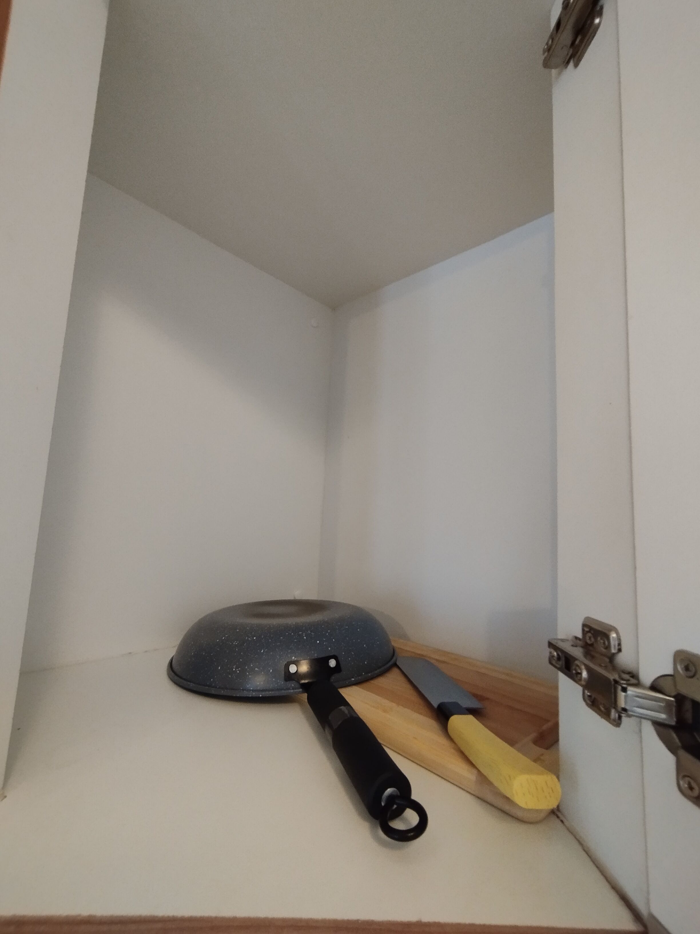 A kitchen corner with a frying pan and a spatula on the counter.