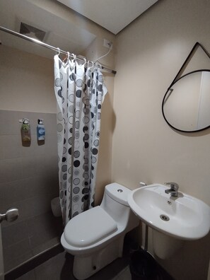 A bathroom with a toilet, sink, and shower curtain. - Cebu Avida Riala T1 1517 IT Park (Cebu City)