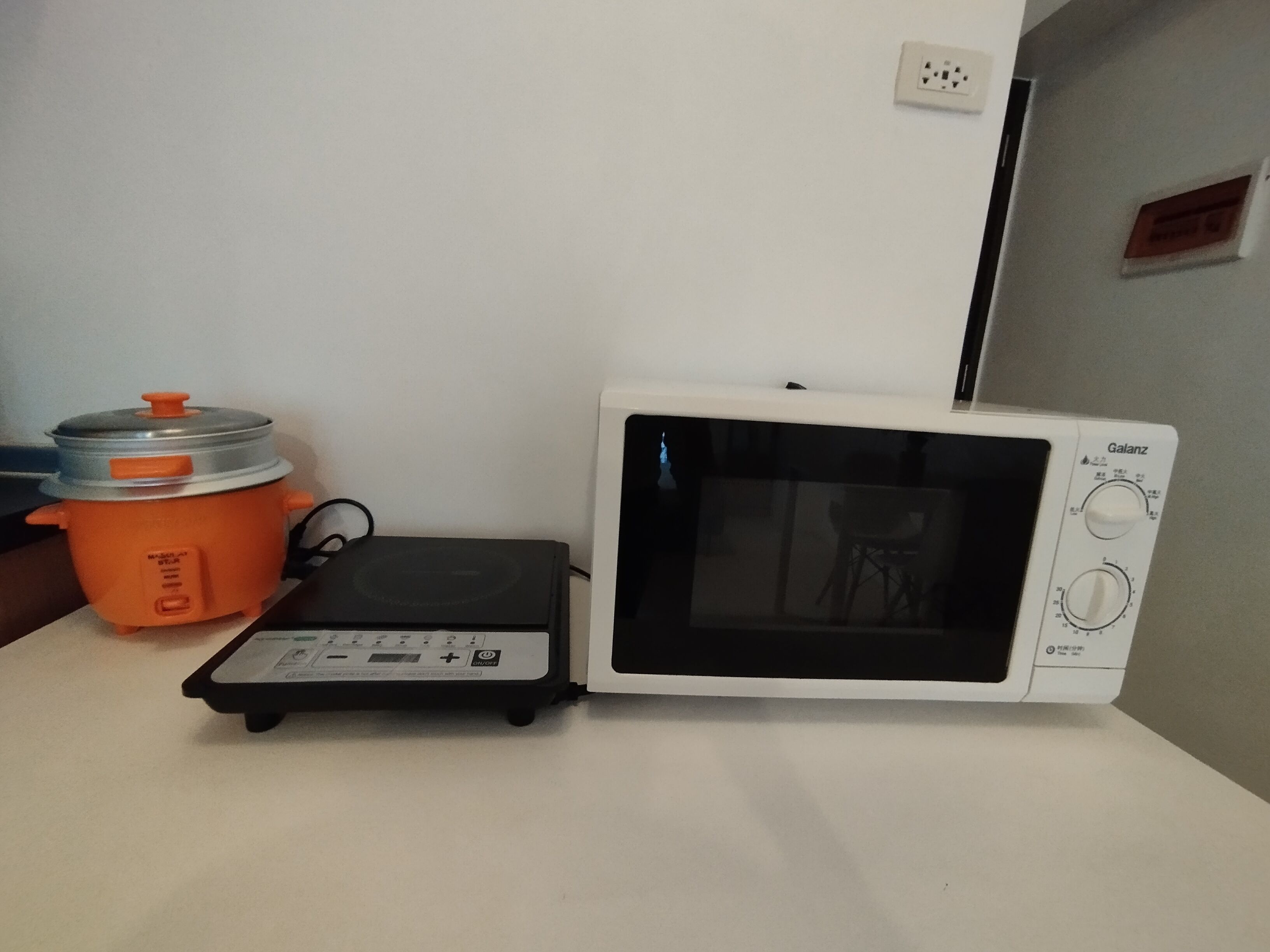 Un horno microondas y una olla de cocción lenta sobre una encimera blanca.