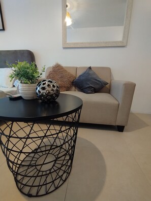 A living room with a round black table, a beige sofa, and a framed picture on the wall. - Cebu Avida Riala T1 1517 IT Park (Cebu City)