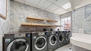 A laundry room with four washing machines, wooden shelves, and patterned walls.