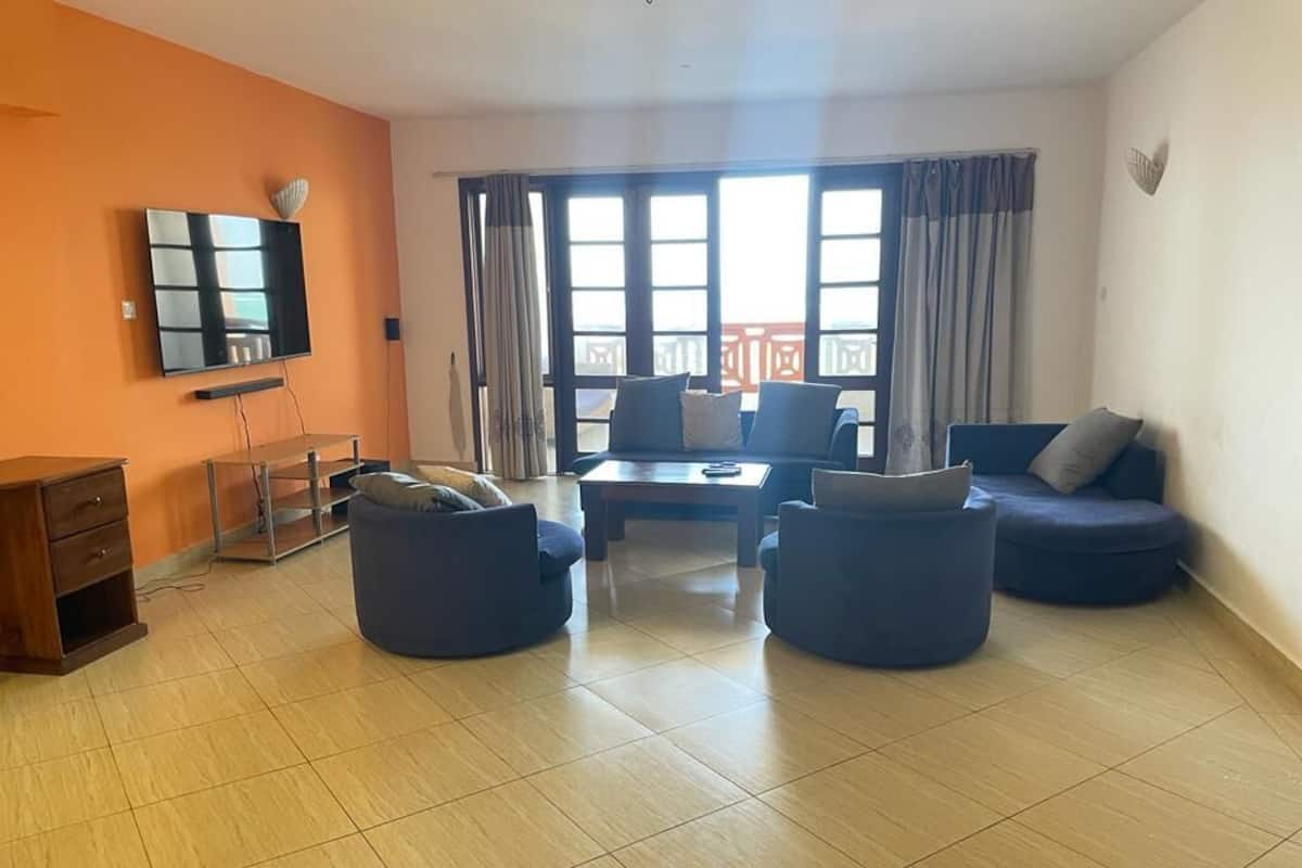 Una sala de estar con televisor, dos sofás, una mesa de centro y un aparador de madera.