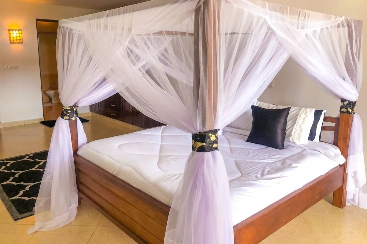 Una cama con dosel, cabecera de madera y alfombra estampada en blanco y negro.