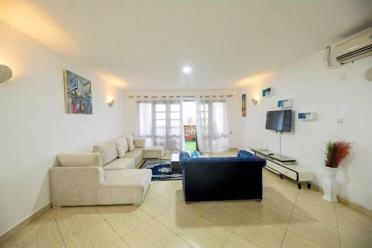 Una sala de estar con un sofá, un sillón azul, un televisor y un cuadro en la pared.