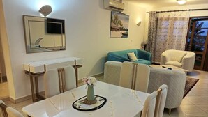 A living room with a white table, a teal sofa, and a white armchair. - Lux Suites Lamera Beachfront Villas  (Mombasa)