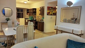 A living room with a sofa and chairs, a dining area with a table and chairs, and a kitchen with cabinets and appliances. - Lux Suites Lamera Beachfront Villas  (Mombasa)