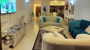 A living room with a television, sofas, a coffee table, and a decorative cabinet. - Lux Suites Lamera Beachfront Villas  (Mombasa)