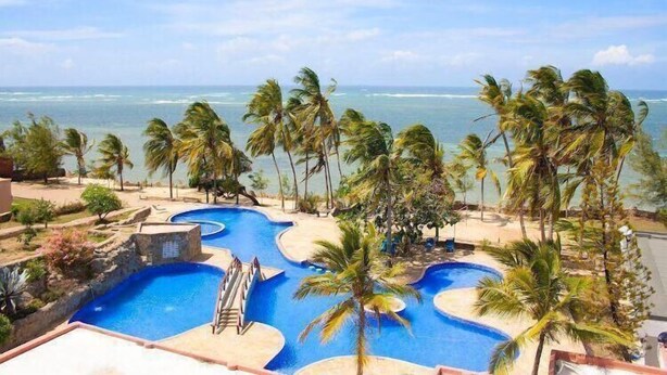 A resort pool area with multiple swimming pools, palm trees, and a view of the ocean. - Lux Suites Lamera Beachfront Villas  (Mombasa)