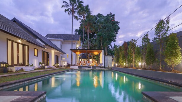 A modern house with a swimming pool, outdoor seating area, and lush greenery. - Olivia Estate (Seminyak)