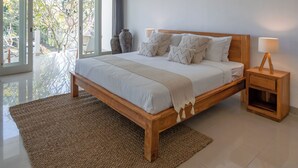 A spacious bedroom with a large bed, wooden headboard, and a woven ceiling light fixture. - Olivia Estate (Seminyak)