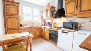 Una cocina con armarios de madera, microondas, lavavajillas y una mesa de comedor con sillas.