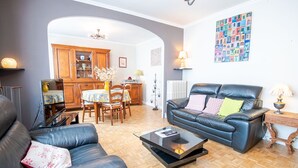 Una sala de estar con un sofá de cuero, una mesa de centro y un comedor con muebles de madera y un florero.