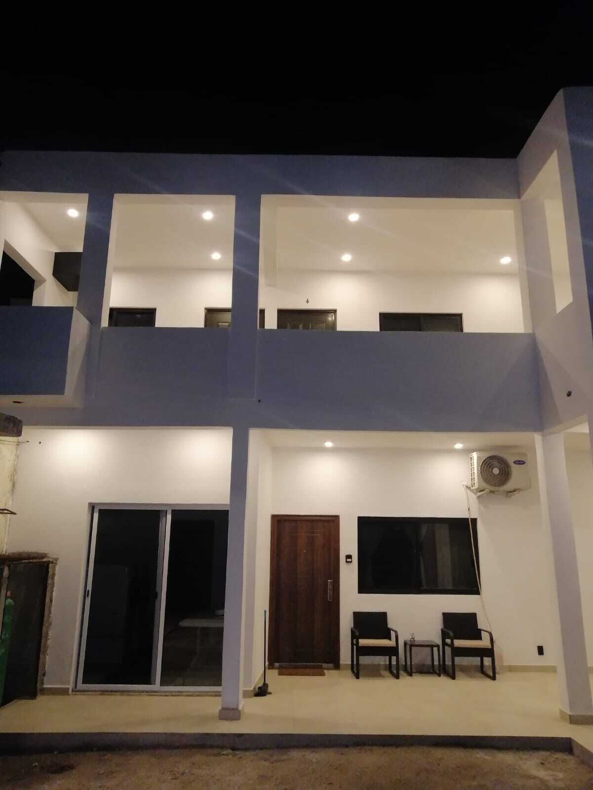 A two-story building with a balcony, large windows, and a door.