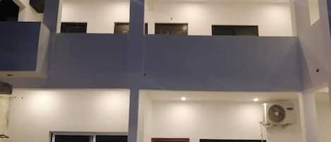 Un bĂątiment Ă deux Ă©tages dotĂ© dâun balcon, de grandes fenĂȘtres et dâune porte.