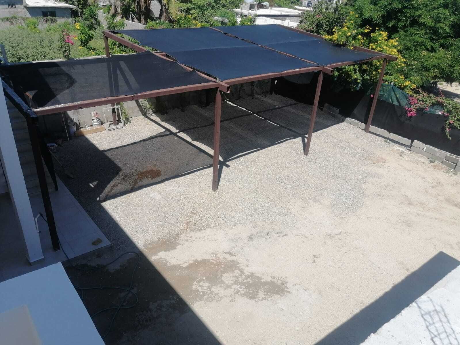 A rooftop with a metal frame structure supporting a large, flat, dark-colored solar panel array.