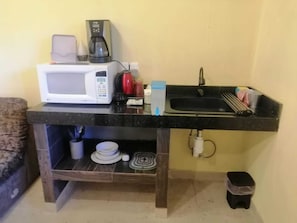 Une petite cuisine équipée d’un four à micro-ondes, d’une machine à café et d’un évier.