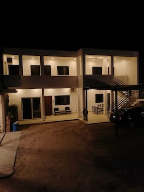 A two-story building with a covered outdoor seating area, a staircase, and a car parked outside.