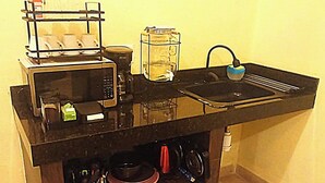 Una cucina con un forno a microonde, una macchina per il caffè e un contenitore di vetro sul piano di lavoro.