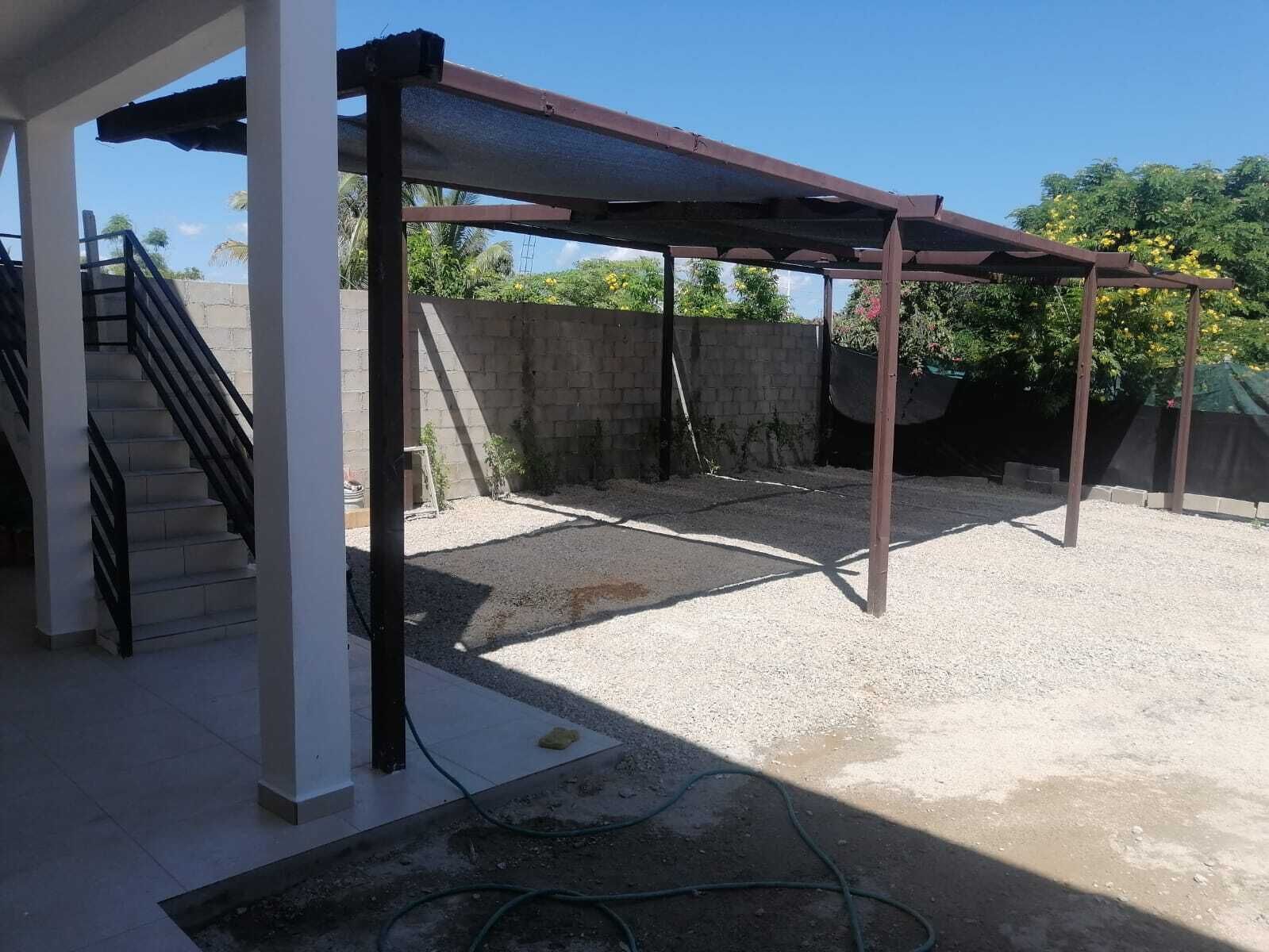 A covered outdoor area with a concrete floor, a staircase, and a metal structure.