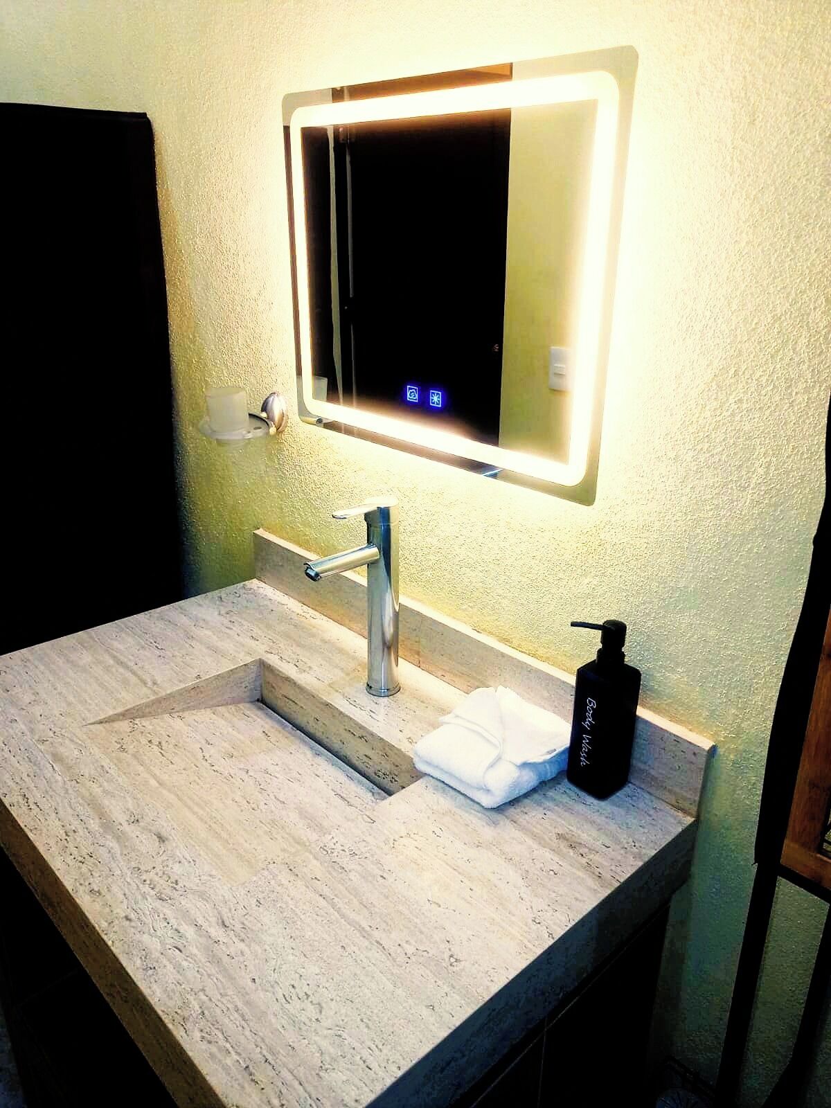 Une salle de bain avec un miroir, un lavabo et une serviette.