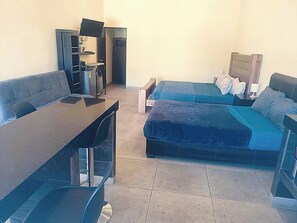 Una habitación con escritorio, dos camas, una silla y televisor.