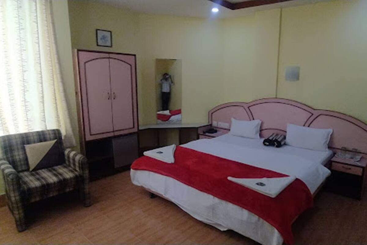 A bedroom with a bed, a chair, a wardrobe, and a nightstand.