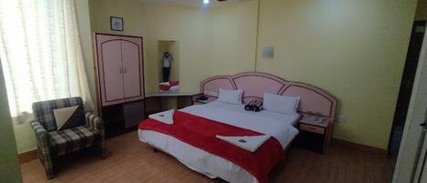 A bedroom with a bed, a chair, a wardrobe, and a nightstand.