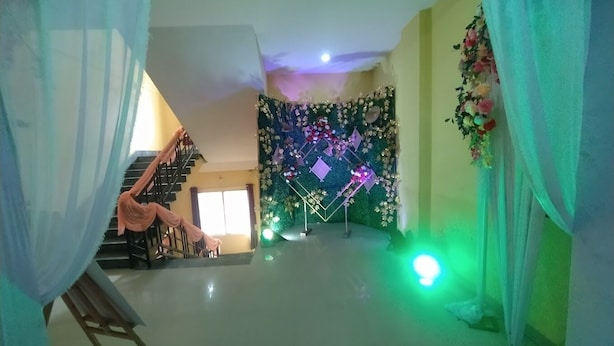 Een kamer met een trap, een muur versierd met bloemen en lichtjes, en een gebied verlicht in groen.