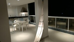 Una cocina moderna con sillas blancas y una mesa de comedor, una hamaca y un balcón con vistas.