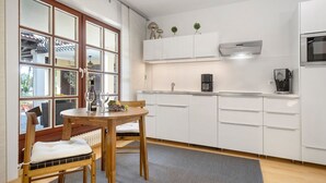 Una cocina moderna con armarios blancos, una mesa de comedor con sillas y un ventanal con vistas al exterior.