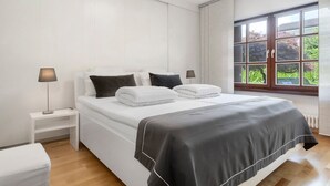 Un dormitorio con cama, mesitas de noche y ventana.