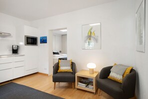 Uma sala de estar moderna com um sofá, uma mesa lateral, um micro-ondas, uma máquina de café e um quadro na parede.