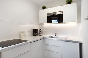 A modern kitchen with white cabinetry, a built-in oven, a coffee maker, and a sink. - Apartment 'Ferienwohnung Whg 2' with Private Terrace, Private Garden and Wi-Fi (Kressbronn am Bodensee)