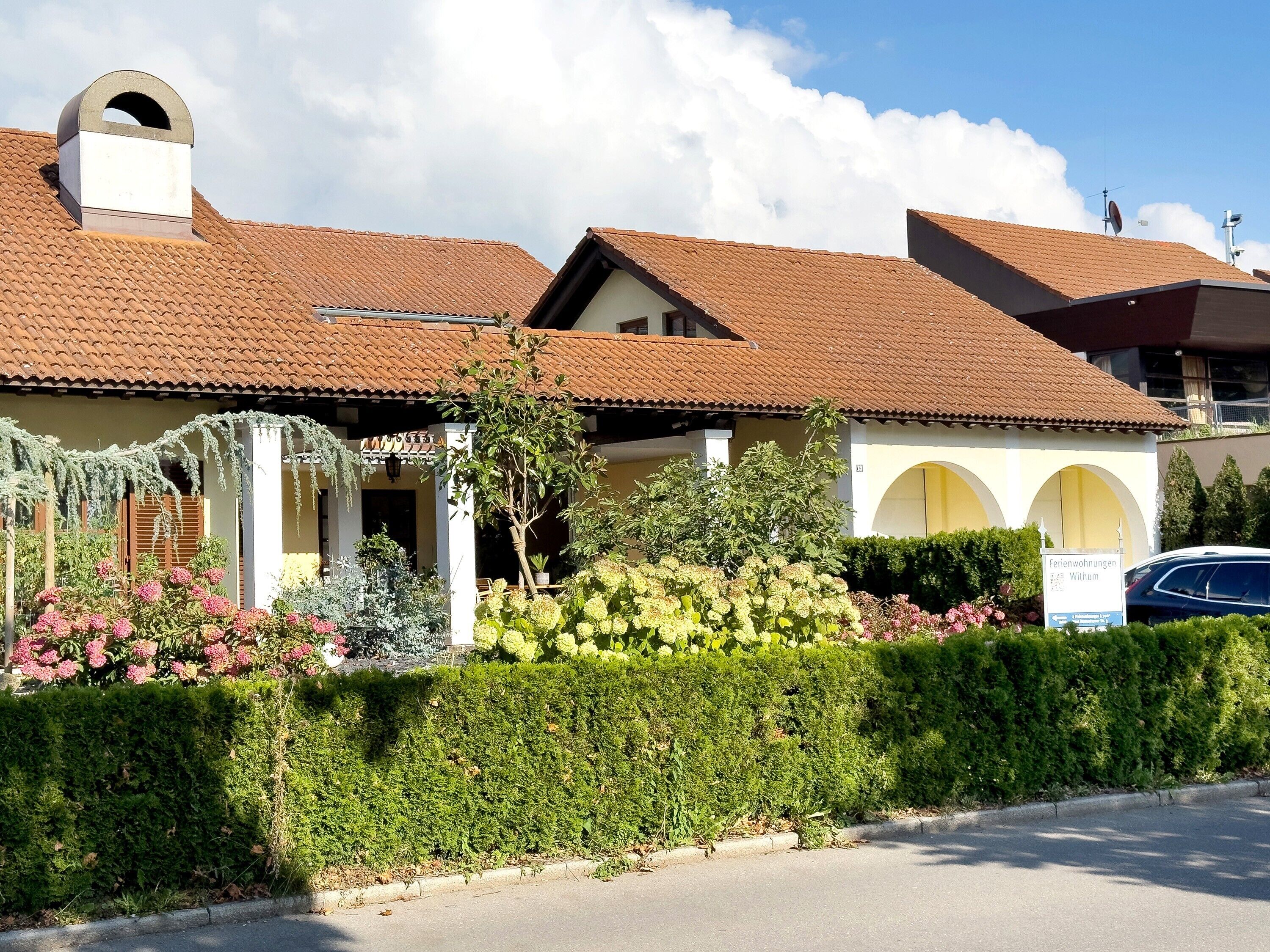 Ein Gebäude mit einem Ziegeldach, einer Veranda und einem Schild, das es als Hotel kennzeichnet.