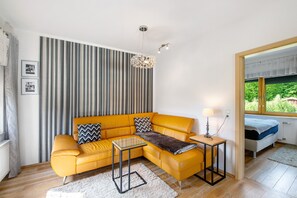 A modern living room with a yellow sofa, a glass coffee table, a lamp, and a view of a garden through a window. - Holiday Apartment "Gabi" with Shared Terrace & Wi-Fi (Malchow)