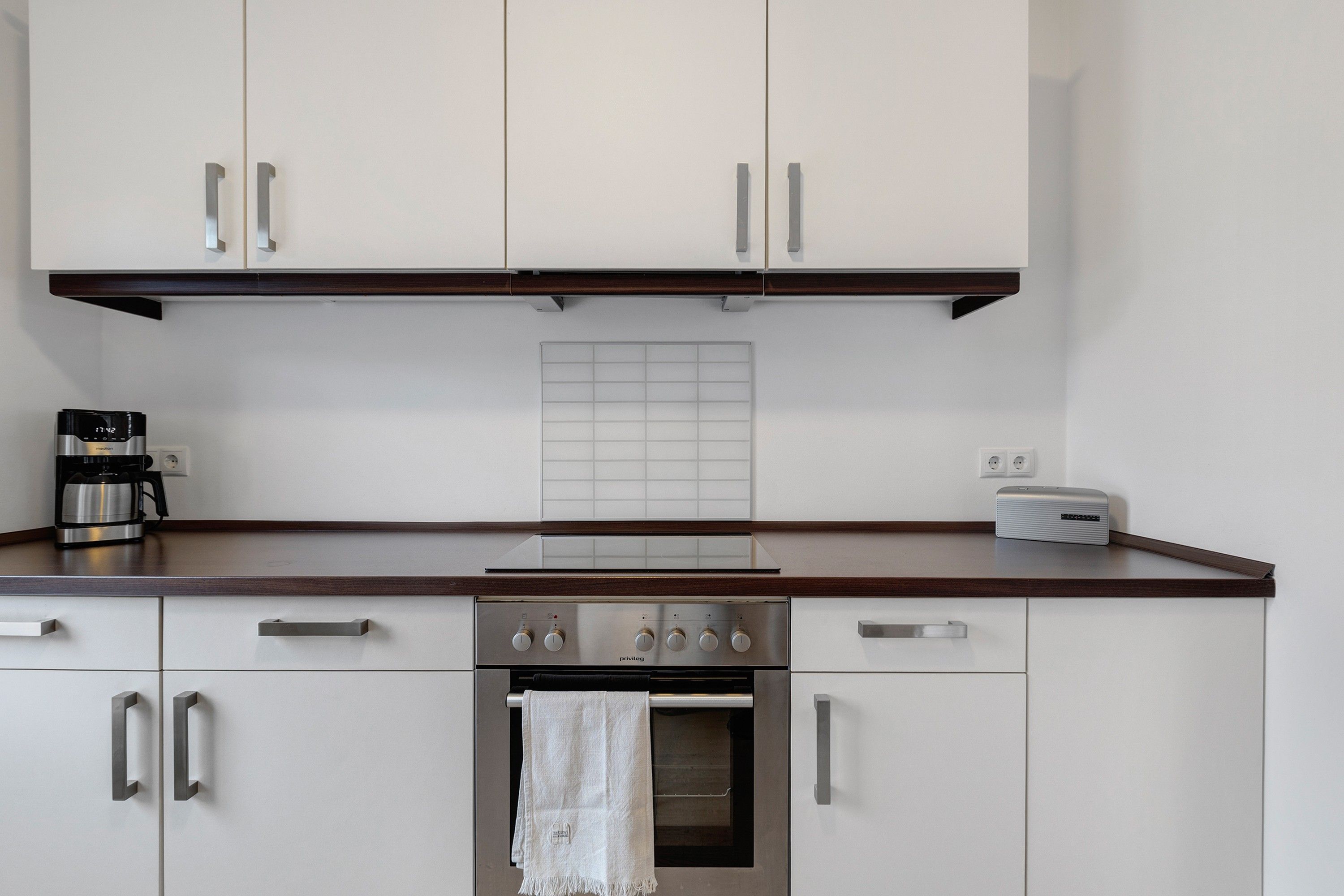 A kitchen with white cabinets, a stainless steel range, a coffee maker, and a toaster.
