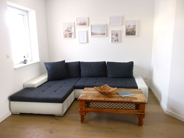 A modern living room with a sectional sofa, a wooden coffee table, and framed artwork on the wall.