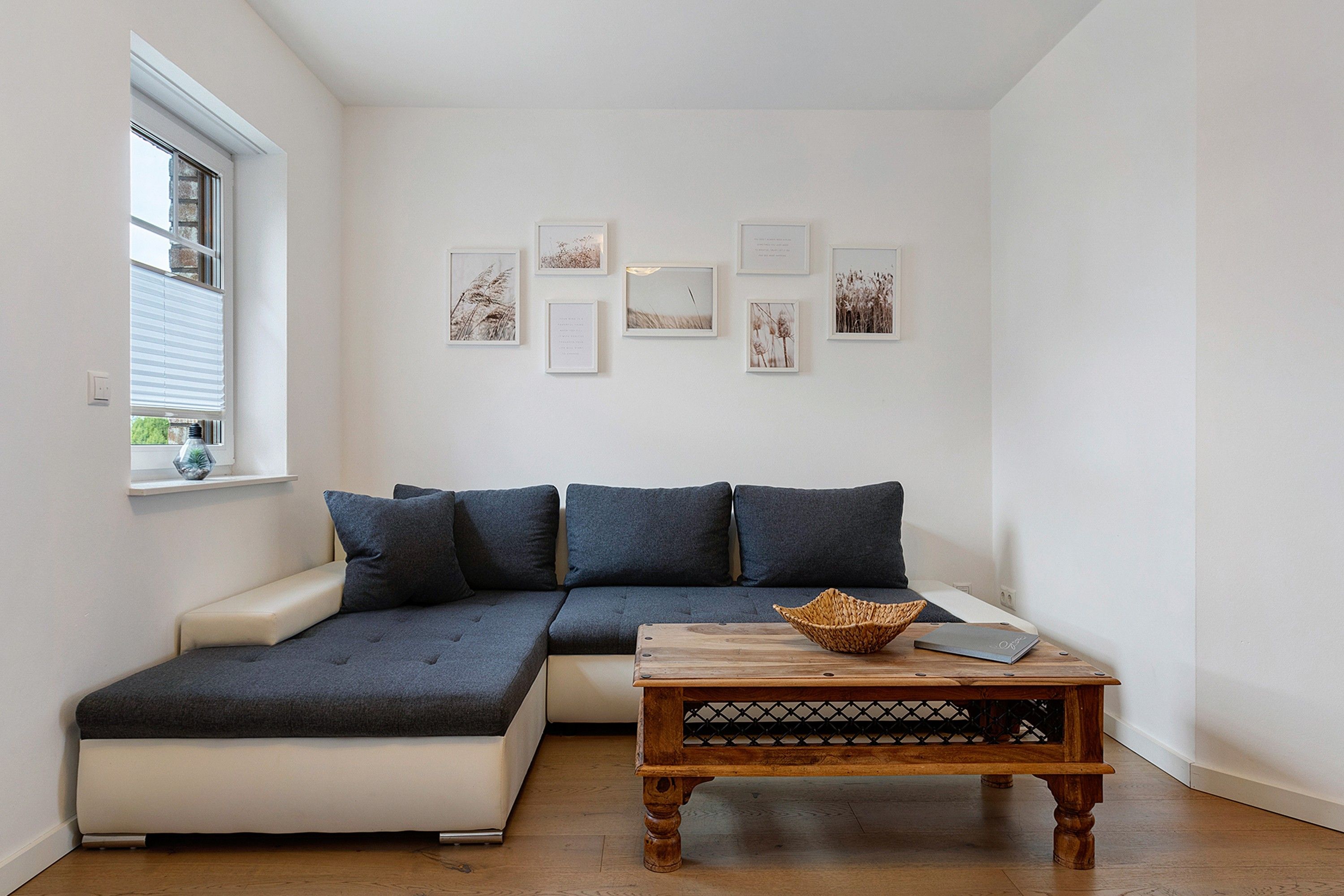 A modern living room with a sectional sofa, a wooden coffee table, and wall-mounted artwork.