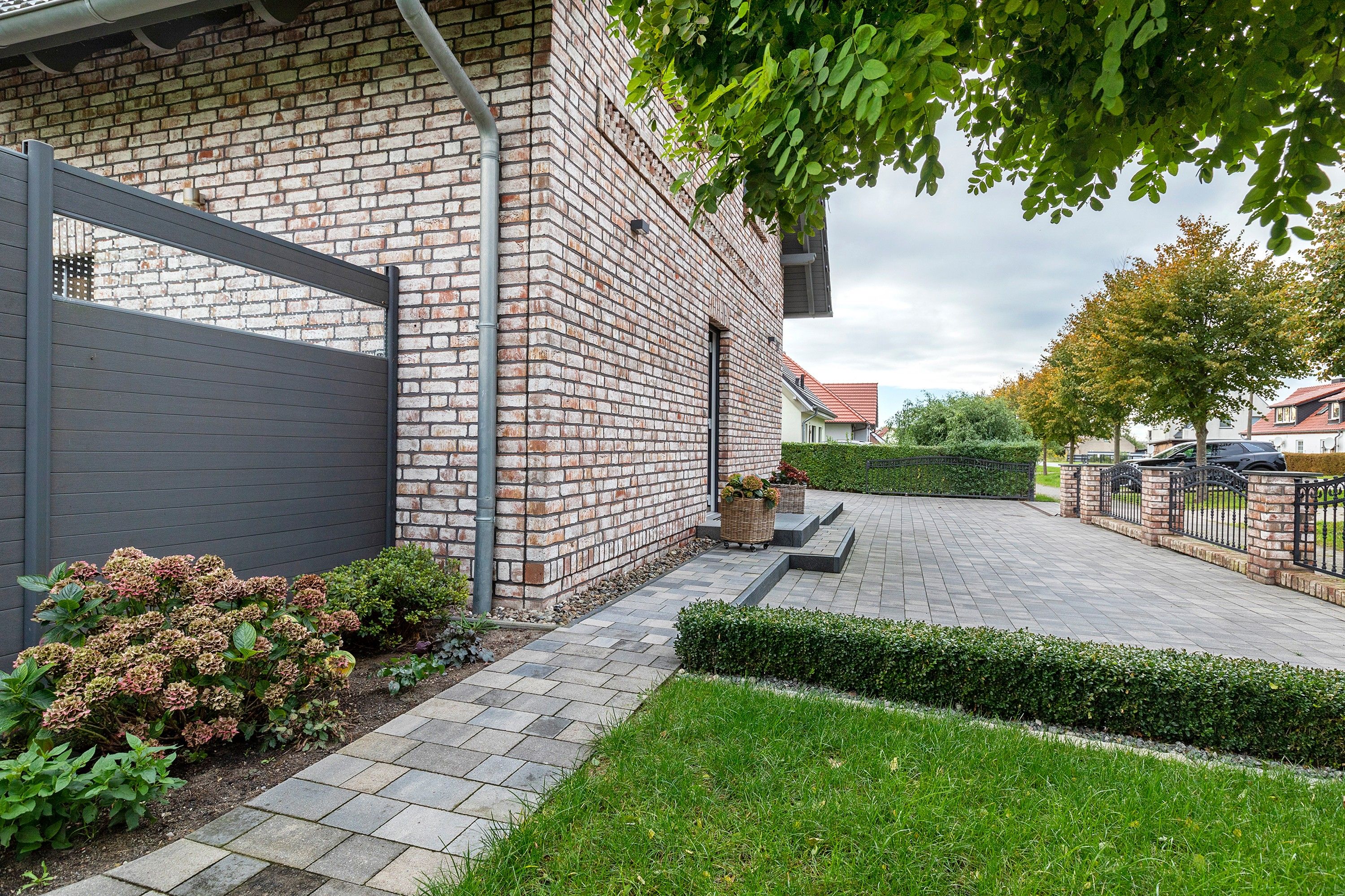 A residential building with a brick facade, a paved driveway, and a well-maintained lawn.