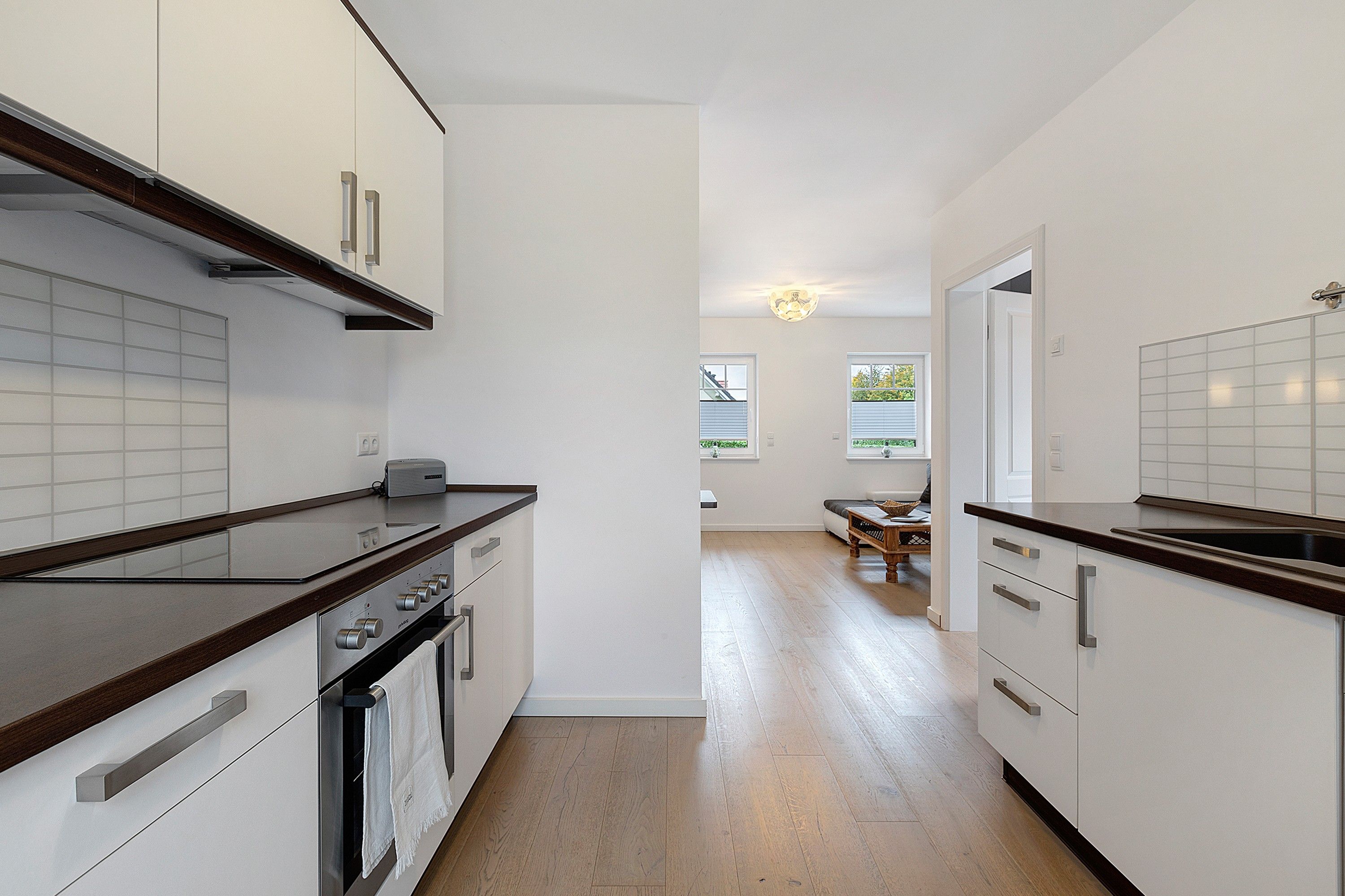 Une cuisine moderne avec des meubles blancs, un plan de travail en bois et un four encastré.