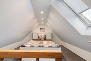 A small, sloped ceiling room with a bed, a bench, and a skylight. - Holiday Home 'Melody' with Private Terrace and Wi-Fi (Ralswiek)